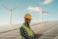 Young engineer watching on digital tablet the new green plan for alternative energy with wind turbine and solar panel Royalty Free Stock Photo