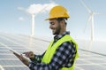 Young engineer watching on digital tablet the new green plan for alternative energy with wind turbine and solar panel Royalty Free Stock Photo