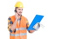 Young engineer wearing helmet with clipboard calling on cellphone Royalty Free Stock Photo