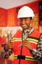 Young engineer wearing square pattern flanel shirt with red safety vest, holding showerhead and pliars smiling to camera