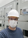 Young engineer working in electrical substation wearing a face mask. Royalty Free Stock Photo