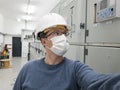 Young engineer working in electrical substation wearing a face mask. Royalty Free Stock Photo