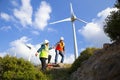 Young engineers looking and checking wind turbines at field Royalty Free Stock Photo