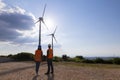 Young engineers looking and checking wind turbines at field Royalty Free Stock Photo