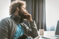 A young entrepreneur brings down accounting. The man takes notes in a notepad and looks at the computer screen sitting Royalty Free Stock Photo