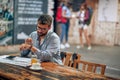 Young entrepreneur businessman with glasses sitting alone at cafe looking at his watch enjoying coffee Royalty Free Stock Photo