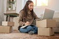 Young entrepreneur, Sitting on the floor and working at home. Checking orders from customers by laptop and writing customer addres