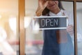 A young entrepreneur or a waitress hanging open sign on the shop front door