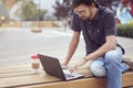 Young entrepreneur working at the park outside on wooden bench. Concept of successful busyness people Royalty Free Stock Photo