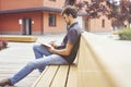 Young entrepreneur working at the park outside on wooden bench. Handsome man wearing glasses using book, writing text. Royalty Free Stock Photo