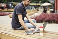 Young entrepreneur working at the park outside on wooden bench.Young entrepreneur working at the park outside on wooden bench.