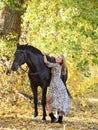 Young equestrian woman walking horse in autumn park Royalty Free Stock Photo