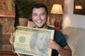 Young ethnic man holding gigantic 100 dollars bill Royalty Free Stock Photo