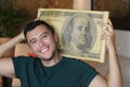 Young ethnic man holding gigantic 100 dollars bill Royalty Free Stock Photo