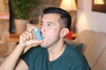 Young ethnic man using asthma inhaler at home Royalty Free Stock Photo