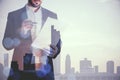 Young businessman doing paperwork on blurry city background. Success, future and ceo concept. Double exposure Royalty Free Stock Photo