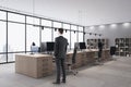 Young european businessman standing in modern wooden and concrete coworking office interior with furniture and window with city Royalty Free Stock Photo