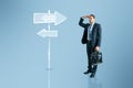 Young businessman thinking which path to choose on blue background with sign sketch. Different direction concept Royalty Free Stock Photo