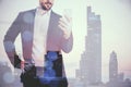 Young businessman using mobile phone on blurry city background. Success, future and ceo concept. Double exposure Royalty Free Stock Photo