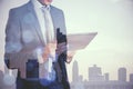 Young businessman using tablet on blurry city background. Success, future and ceo concept. Double exposure Royalty Free Stock Photo