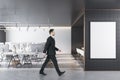 Young european businessperson walking in modern coworking office interior with empty white mock up poster, equipment, furniture