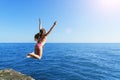 Young european cute girl is jumping and flying to the calm blue sea from concrete breakwater towards summer soft sun Royalty Free Stock Photo