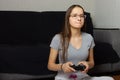 Young european dark-haired teen girl plays video games at home.