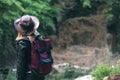 Young european female tourist with backpack and cowboy hat looking at the river washed away the bridge, the crossing was