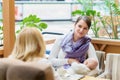 Young european gay couple or friends women with infant is sitting on bench close to white baby carriage while one of them breastfe Royalty Free Stock Photo