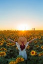 Young european girl in white dress staying at the sunflowers field in pose of faith