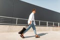 Young european hipster man in a white shirt in blue jeans in fashionable sandals with a black bag walks on the street Royalty Free Stock Photo