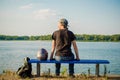 Young european man in black shirt and jeans sits on bench near river with a motorcycle helmet and looks at sunset sun Royalty Free Stock Photo