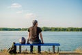 Young european man in black shirt and jeans sits on bench near river with a motorcycle helmet and looks at water Royalty Free Stock Photo