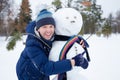 Young european man in warm clothes making snowman from snow outdoor Royalty Free Stock Photo