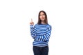 young european model woman wears a sweater with a sailor striped pattern points her hand to the side on a white