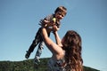 Young European mother throws her three year old son up with both hands and he laughs. Mom plays with child in fresh air in clear Royalty Free Stock Photo