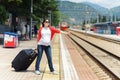 Young european pregnant woman with heavy baggage trying to stop train on railway station for traveling at sunny day Royalty Free Stock Photo