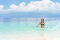 Young european woman in bikini with good mood splashing and dancing in beautiful tropical calm sea under cloudy soft sky Royalty Free Stock Photo