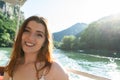 Young european woman is boating on a lake. Girl smiling showing teeth, sitting into small boat at sunset on the river in the