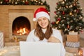 Young European woman celebrating Christmas at home due to corona virus epidemic, having video call with close person, looking