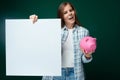 Young European woman dressed in a plaid shirt and jeans holds a piggy bank and talks about investments Royalty Free Stock Photo