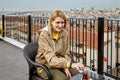 Young European woman drinks tea on roof of hotel overlooking cityscape of Istanbul Royalty Free Stock Photo