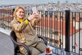 Young European woman drinks tea on roof of hotel overlooking the cityscape of Istanbul and takes a selfie using a mobile phone or Royalty Free Stock Photo