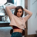 Young European woman in a glamorous stylish sweatshirt posing in a room with a vintage wooden white mirror. Attractive girl