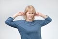 Young european woman plugging ears, looking up, pretending not to hear what she is told