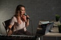 A young European woman sings into a microphone and accompanies on an electronic piano. The girl shoots a video blog