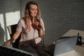 A young European woman sings into a microphone and accompanies on an electronic piano. The girl shoots a video blog