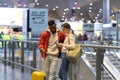 Young woman with mobile phone helping african man traveler in airport, showing direction on map Royalty Free Stock Photo