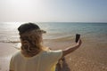 Young european woman taking selfie at morning sunny beach