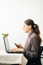 Young European woman, working from home during the virus quarantine, on her laptop.a small green lovebird parrot sits on a laptop Royalty Free Stock Photo